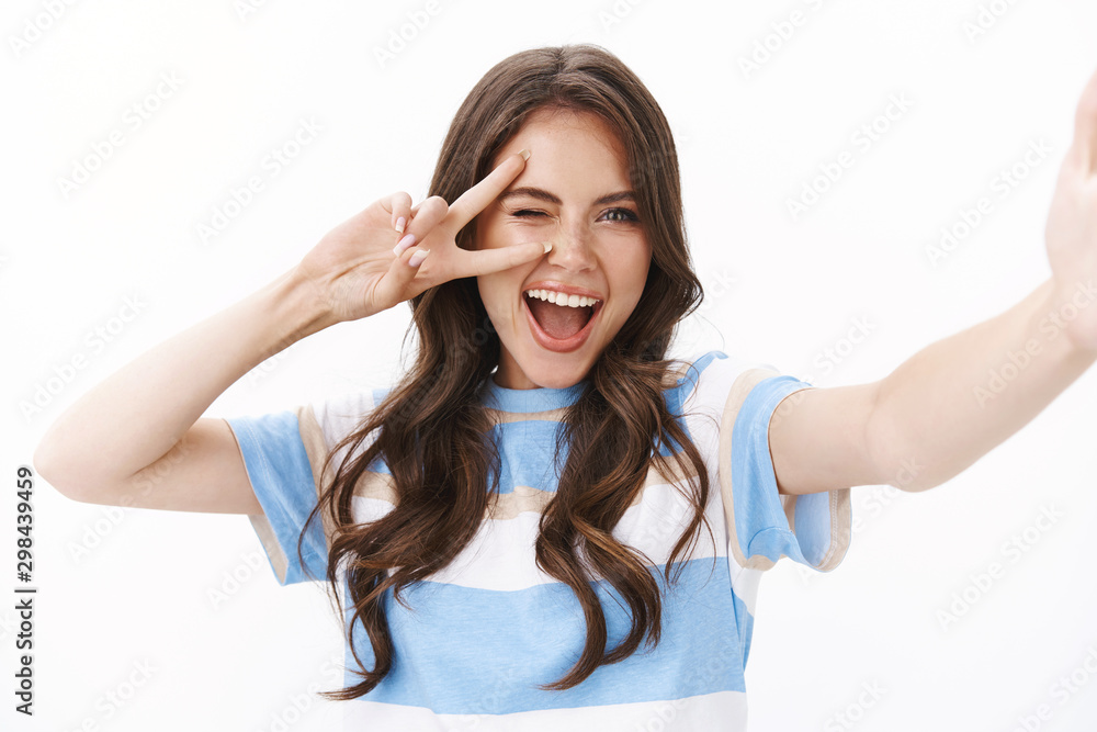 Cheerful enthusiastic woman send girlfriend pics from vacation, summer travel, hold hand camera, taking selfie smartphone, smiling excited show peace victory sign, stand white background Cheerful enthusiastic woman send girlfriend pics from vacation, summer travel, hold hand camera, taking selfie smartphone, smiling excited show peace victory sign, stand white background