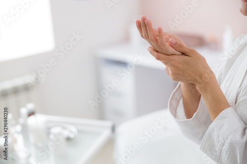 Young woman massaging her hand against blurred background