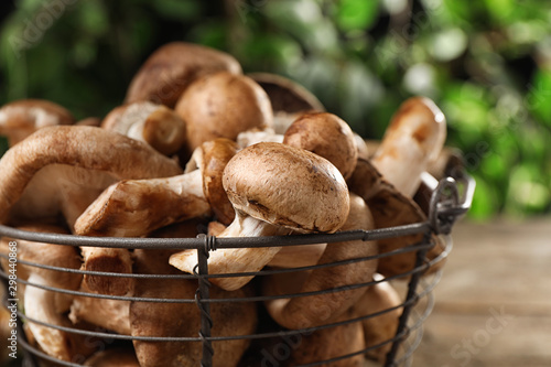 Different wild mushrooms in metal basket on table, closeup