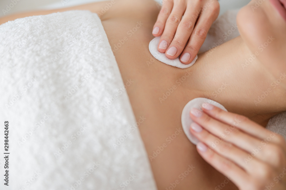 Cosmetologist wiping lady skin with soft cotton pads