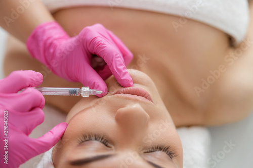 Beautician in sterile gloves making injection in lady lips