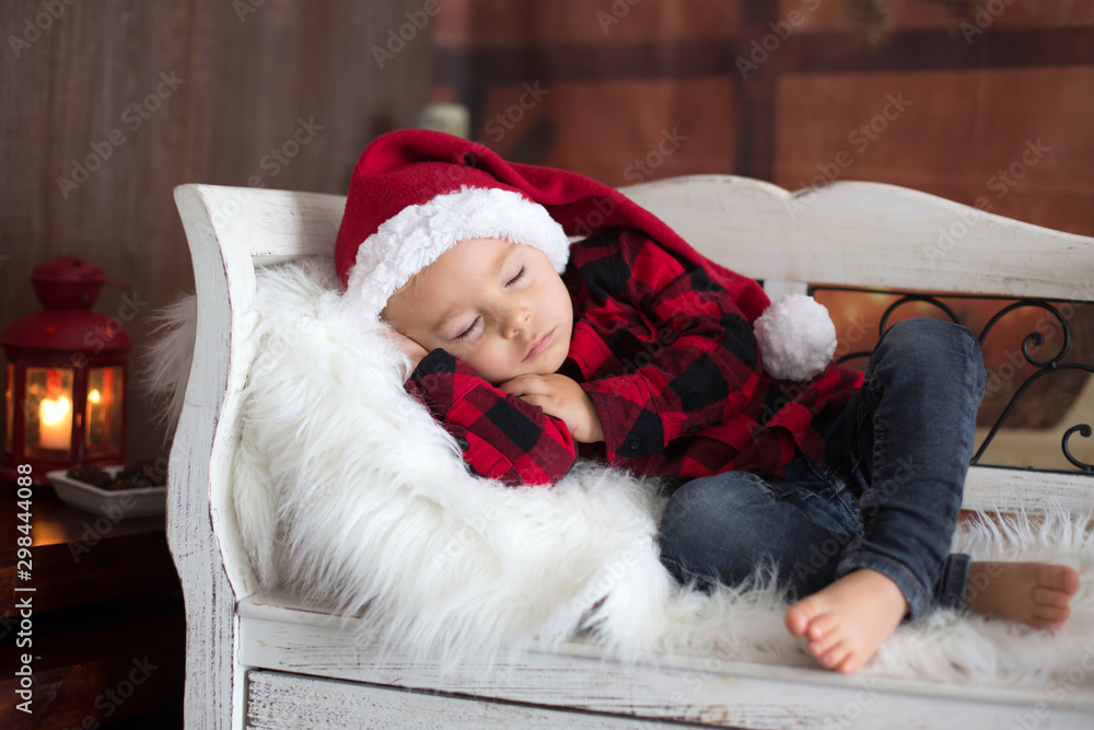 Sweet blonde toddler boy, sleeping with letter to Santa in hand, wishing present for the holidays