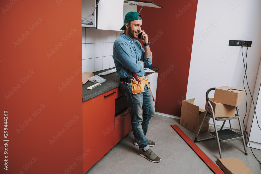 Smiling man talking on the phone at home Smiling man talking on the phone at home