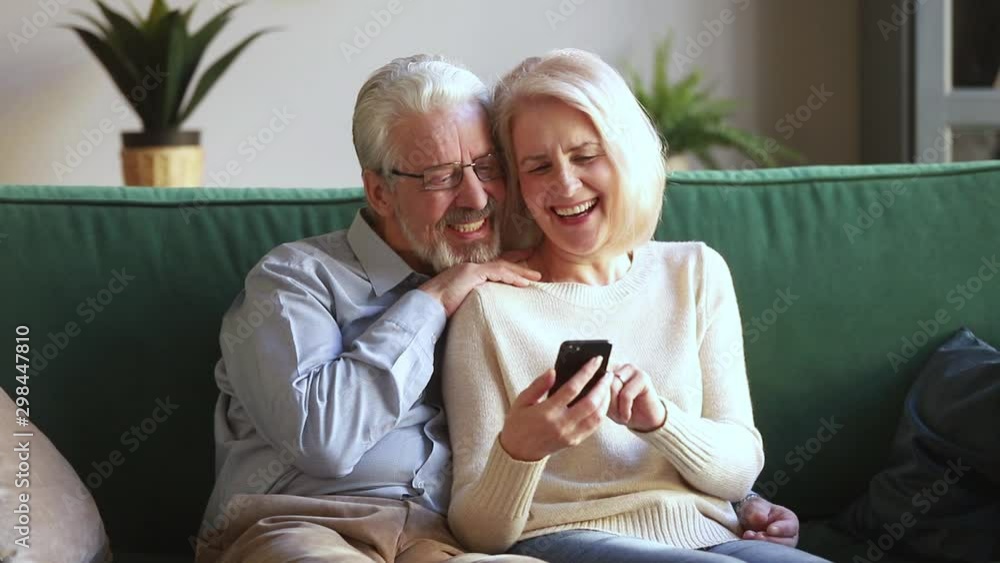 Old wife and husband sitting on couch using smartphone apps Old wife and husband sitting on couch using smartphone apps