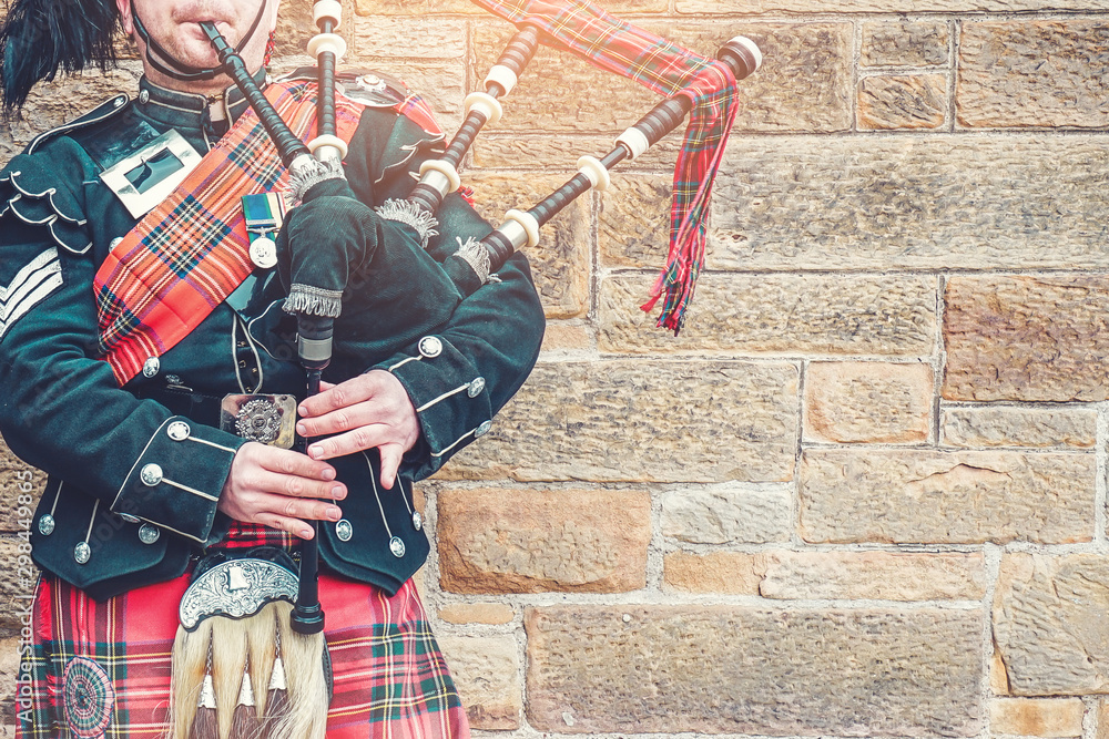 Ταπετσαρία EDINBURGH, SCOTLAND, 24 March 2018 , Scottish bagpiper dressed in traditional red and black tartan dress stand before stone wall