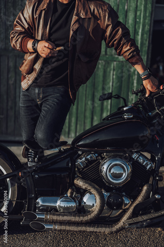 Handsome biker with cigar standing near garage outdoors