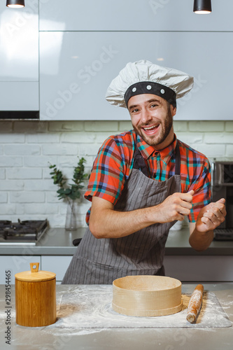 Man dressed in a chef costume, dances in the kitchen happy.