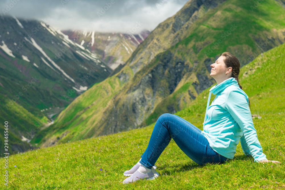 Happy woman resting and admiring the mountains in the campaign to the Caucasus Happy woman resting and admiring the mountains in the campaign to the Caucasus