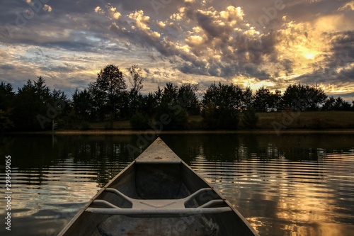 Point of view of a canoeist paddling on a serene country pond at sunset © Jennifer