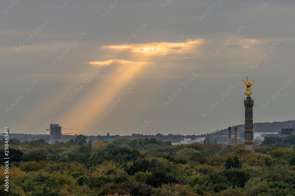 Sunbeams filter through the clouds on the Tiergarten Park in Berlin, Germany, near the Victory Column