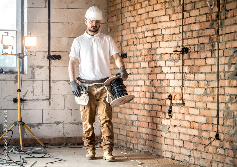 Fototapeta premium Electrician with tools, working on a construction site. Repair and handyman concept.