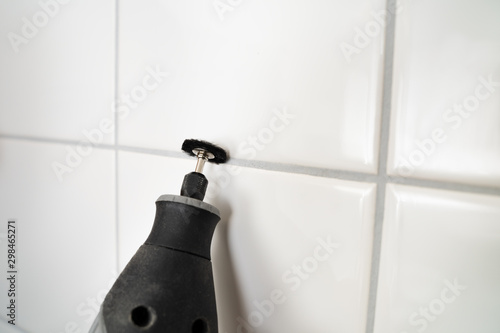 Obraz na plátně Person Cleaning The White Tile Using Power Tool