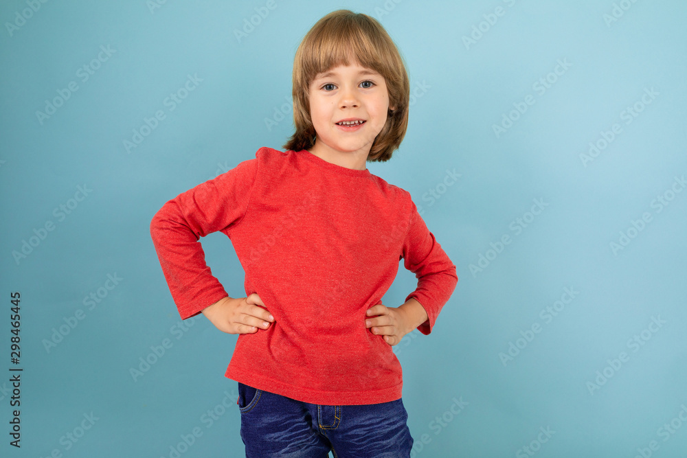 a teenage caucasian boy in a red jaket keep hands on his belt, picture isolated on blue background a teenage caucasian boy in a red jaket keep hands on his belt, picture isolated on blue background