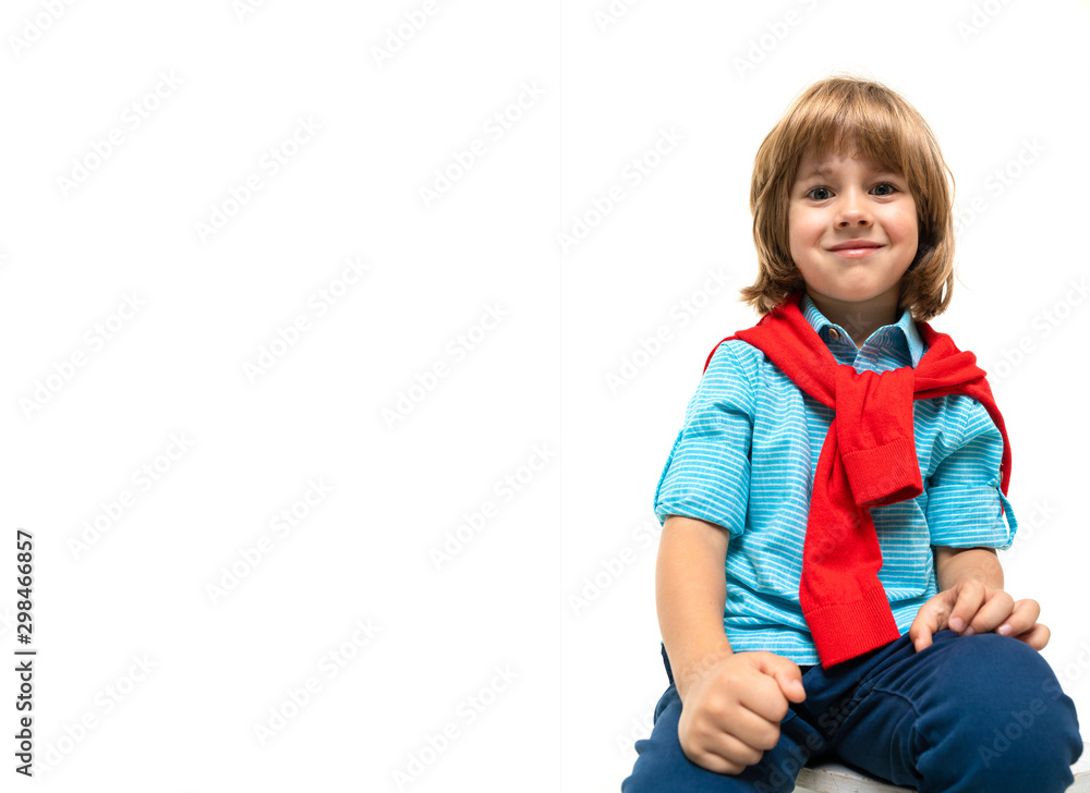 Little caucasian boy sits on a chair with red sweatshot around his neck isolated on white background Little caucasian boy sits on a chair with red sweatshot around his neck isolated on white background