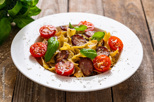 Tagliatelle with sausages on wooden table
