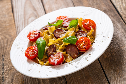 Tagliatelle with sausages on wooden table