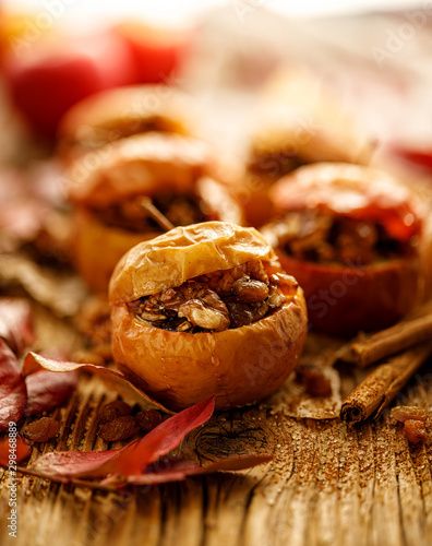 Fototapeta Baked apples stuffed with nuts, raisins and seeds with honey and cinnamon on a wooden table, close-up