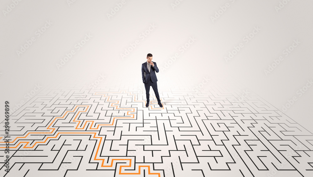 Young entrepreneur standing in a middle of a labyrinth with the solution Young entrepreneur standing in a middle of a labyrinth with the solution