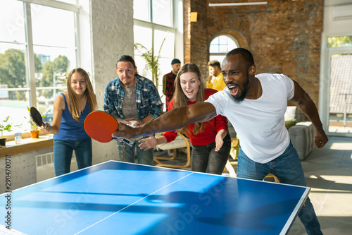Cuadro en lienzo Young people playing table tennis in workplace, having fun