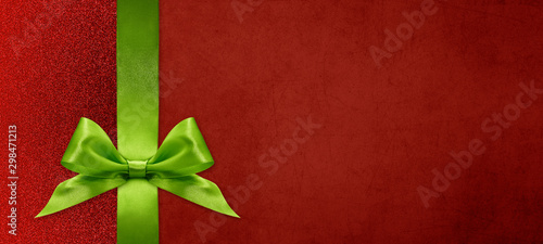gift card wishes merry christmas background with green ribbon bow on red shiny vibrant color texture template with blank copy space