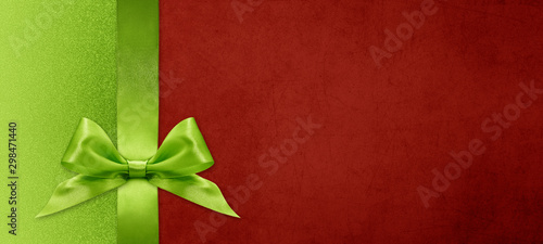 gift card wishes merry christmas background with green ribbon bow on red shiny vibrant color texture template with blank copy space