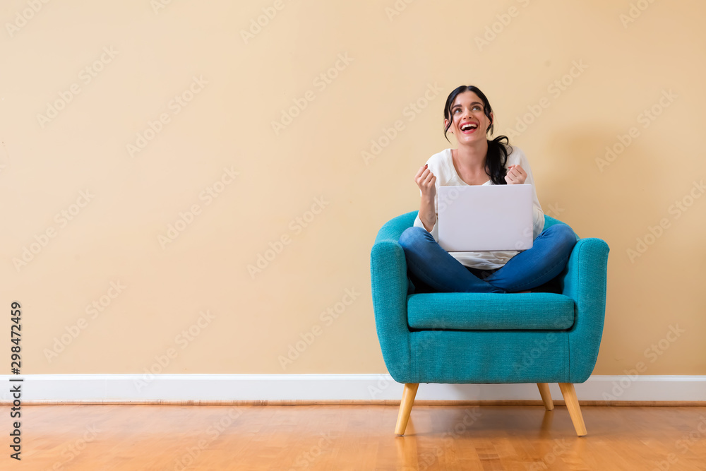 Young woman with a laptop computer with successful pose sitting in a chair Young woman with a laptop computer with successful pose sitting in a chair