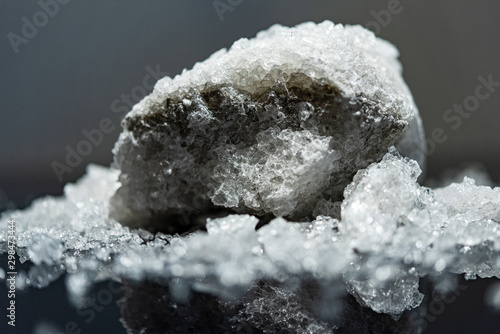 Large crystal of salt on black reflective surface; selective focus; natural edible salt photo