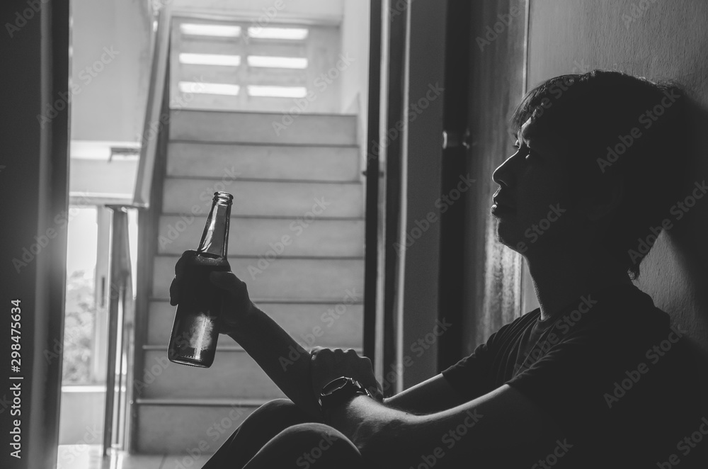 The silhouette of young men holding a bottle of alcohol beer at the old ...