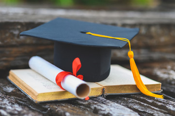 Black graduates hat and yellow tassel place an old book