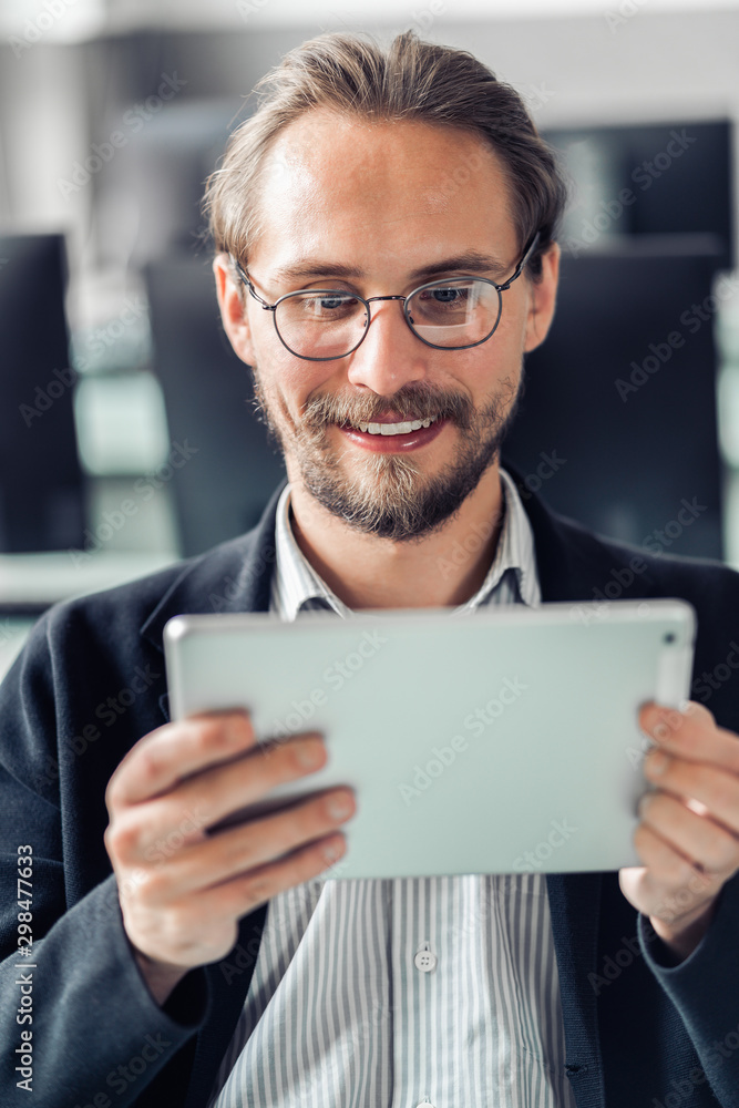 Young handsome man in glasses reading a tablet at work. Young handsome man in glasses reading a tablet at work.