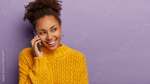 Photos Smiling hipster girl with happy expression uses mobile application for making co