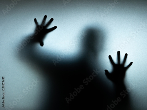 The scary black shadow is behind the glass. Halloween concept.
