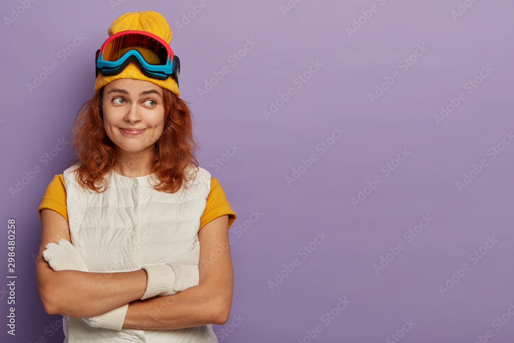 Φωτογραφία Indoor shot of happy redhead woman keeps hands crossed, wears yellow hat and whi