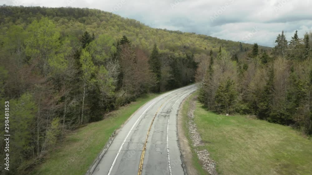 Drone shot, following the road, whilst a red car reveals itself from the bottom of the frame Drone shot, following the road, whilst a red car reveals itself from the bottom of the frame