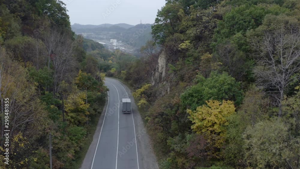 Two lanes road passing in between two cliffs, with cars moving on it. Aerial shot. Two lanes road passing in between two cliffs, with cars moving on it. Aerial shot.