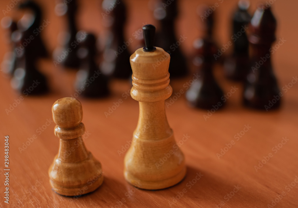 White king and pawn standing on the table in front of the black chess pieces. White king and pawn standing on the table in front of the black chess pieces.