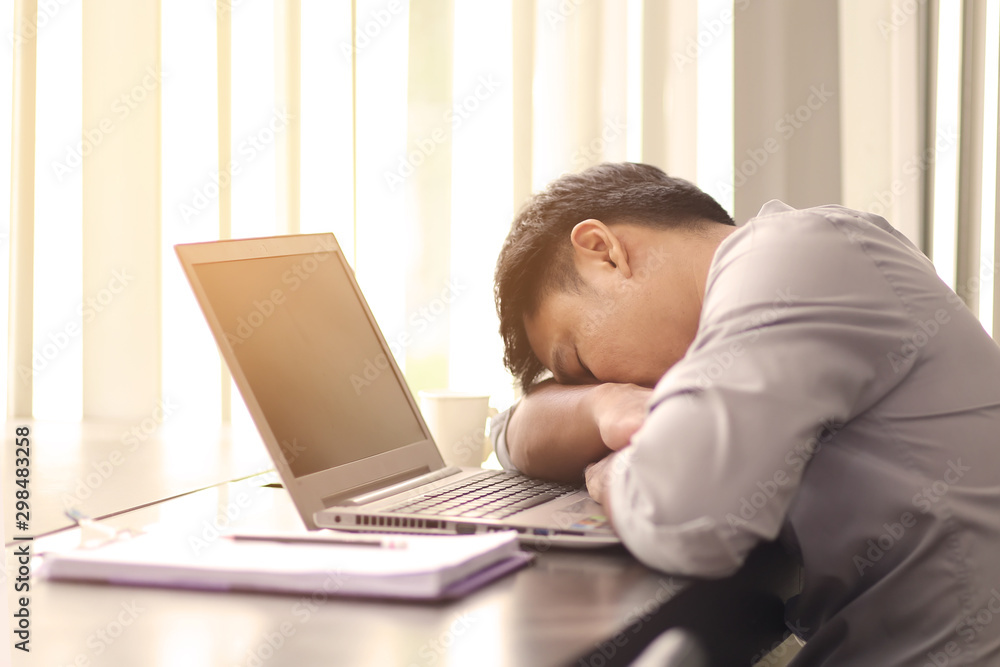 Asian office worker sleeping on a desk with a laptop in the office building. The man is sleeping because of hard work. Asian office worker sleeping on a desk with a laptop in the office building. The man is sleeping because of hard work.