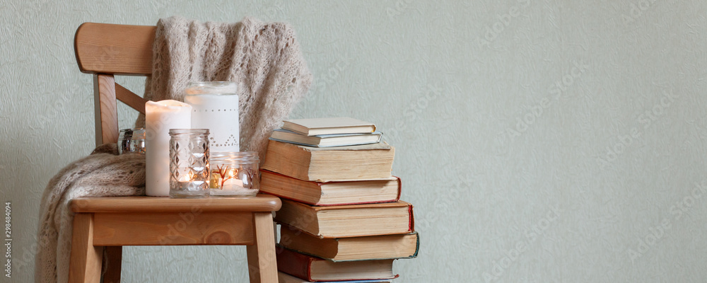 Still life home atmosphere in the interior with a book and candles, home decor elements, the concept of comfort and coziness, autumn winter seasonal weekend relaxation - obrazy, fototapety, plakaty 