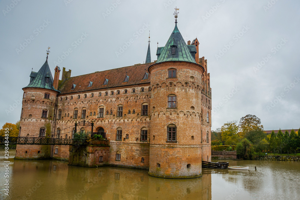 Egeskov, Denmark, Europe: Beautiful landscape with an old Egeskov castle with a bridge by the lake in Denmark in autumn