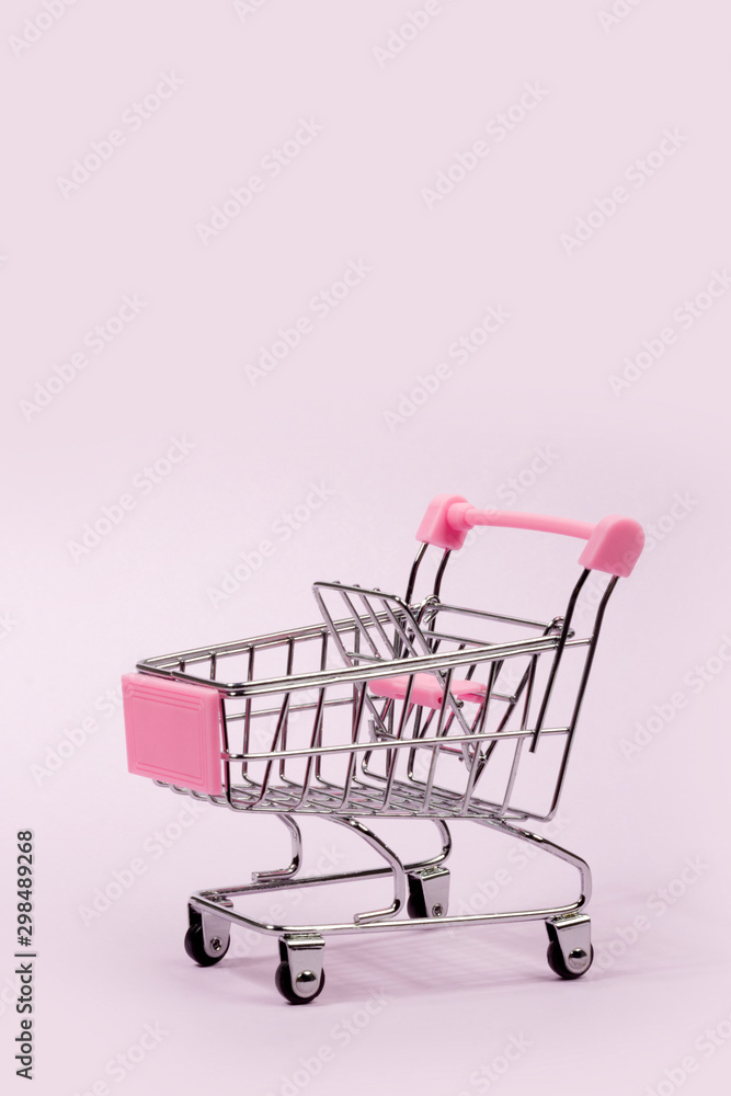 Pastel pink miniature shopping cart on pink background Pastel pink miniature shopping cart on pink background