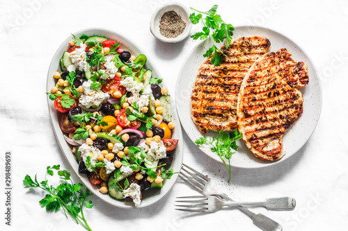 Mediterranean style lunch table - Greek chickpeas salad and pork chops on light background, top view