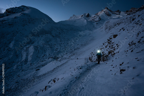 Mountain trekker is ascending on the Thorong La Pass, Nepal, at early morning under night sky.   photo