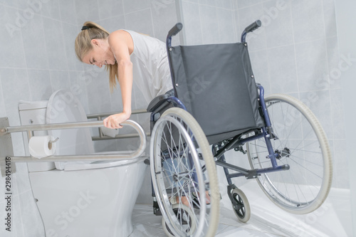 Woman moving from wheelchair to bathroom