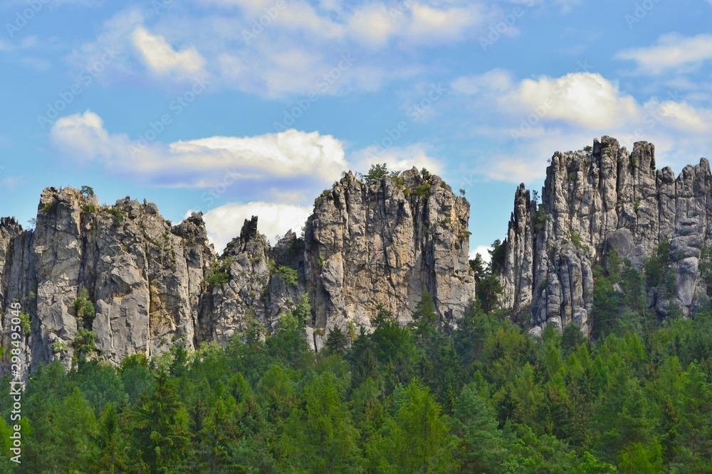 Beautiful sandstone rocks set in forest. Mala Skala, Bohemian Paradise, Czech Republic. Blue sky, white clouds.