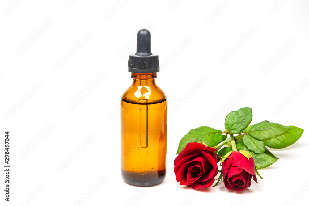 Rose oil in bottle and rose flower isolated on white background. Essential oil product concept. Rose oil in bottle and rose flower isolated on white background. Essential oil product concept.