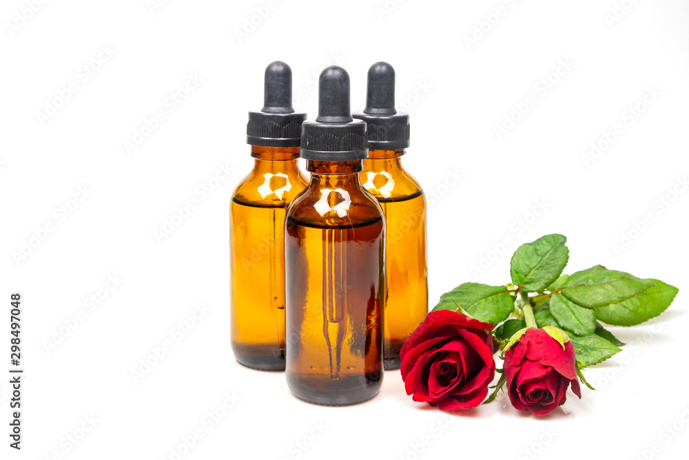 Rose oil in bottle and rose flower isolated on white background. Essential oil product concept. Rose oil in bottle and rose flower isolated on white background. Essential oil product concept.
