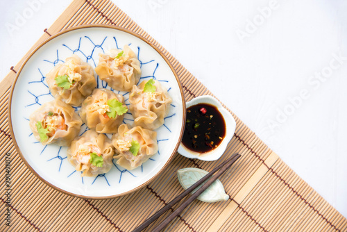 Cantonese Dimsum food cuisine . Fresh  prawn wrapped in yellow dumplings, Steamed Chinese wrapped in yellow Dumplings.White wood flooring  background, space.Chinese popular dim sum food. photo