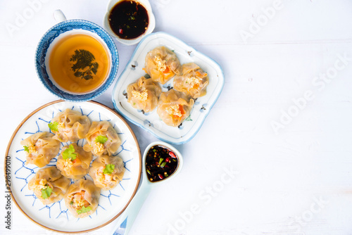 Cantonese Dimsum food cuisine . Fresh prawn wrapped in yellow dumplings, Steamed Chinese wrapped in yellow Dumplings.White wood flooring background, space.Chinese popular dim sum food.