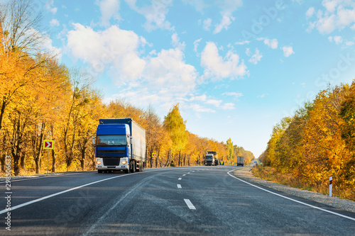 Arriving blue truck on the road in a rural landscape at sunset autumn