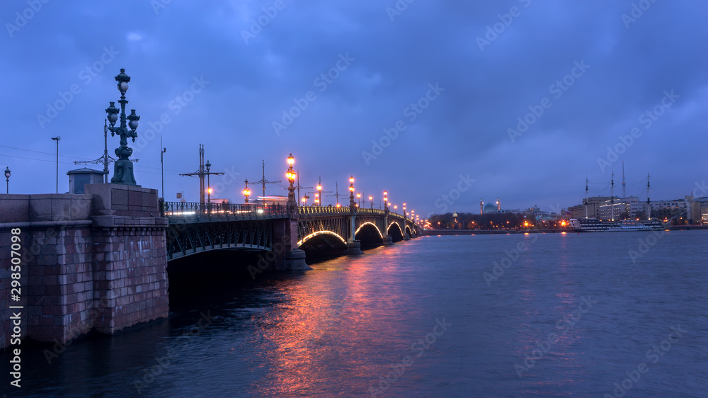 Saint-Petersburg. Russia. Petersburg evening. Trinity Bridge with evening lights is reflected in the Neva River.